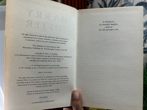 A hand holds a hardcover book of 'Harry Potter and the Half-Blood Prince' by J.K.