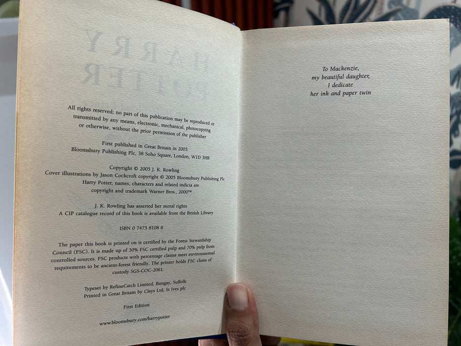 A hand holds a hardcover book of 'Harry Potter and the Half-Blood Prince' by J.K.