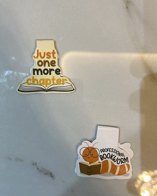 Two stickers on a reflective surface, one with 'Just one more chapter' and another with a bookworm and 'Professional Bookworm'.