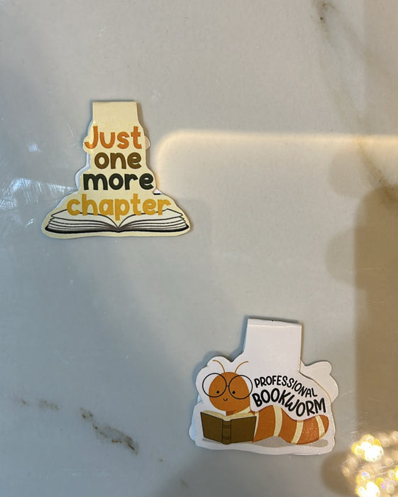 Two stickers on a reflective surface, one with 'Just one more chapter' and another with a bookworm and 'Professional Bookworm'.