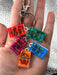 Keychain with book charm keyrings of 'A Court of Thorns and Roses' series held in a hand.